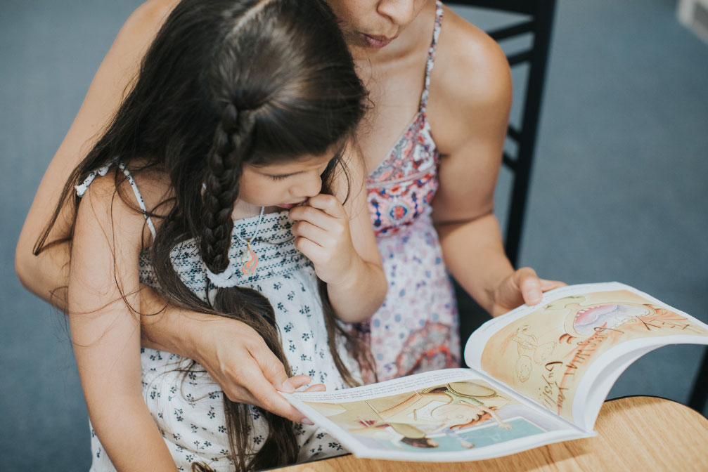 Theraplay: image of girl on woman's lap reading a book